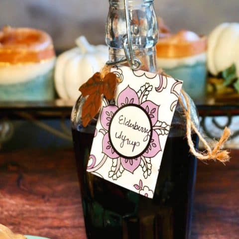 Homemade elderberry syrup recipe in a clear glass jar on a wooden table