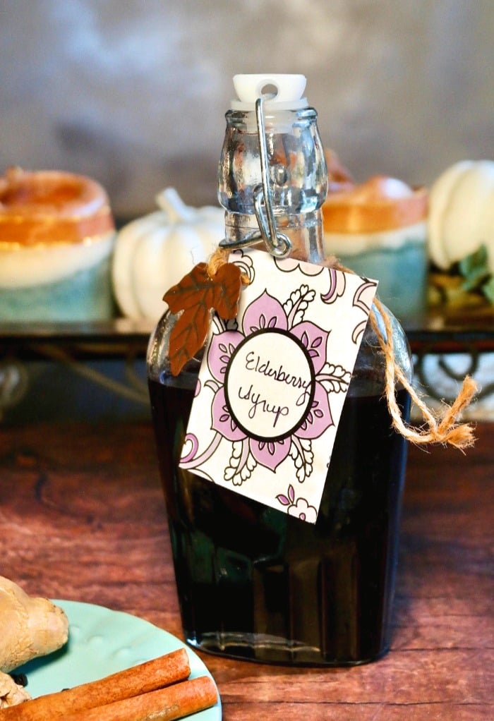 Homemade elderberry syrup recipe in a clear glass jar on a wooden table