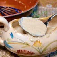 White low carb keto gravy in a gravy serving dish with a spoon scooping it out of the dish