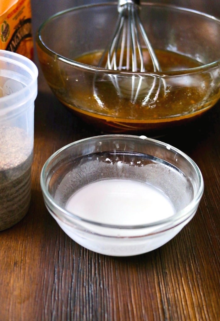 Thickener for stir fry sauce in a small clear bowl with the sauce in the background