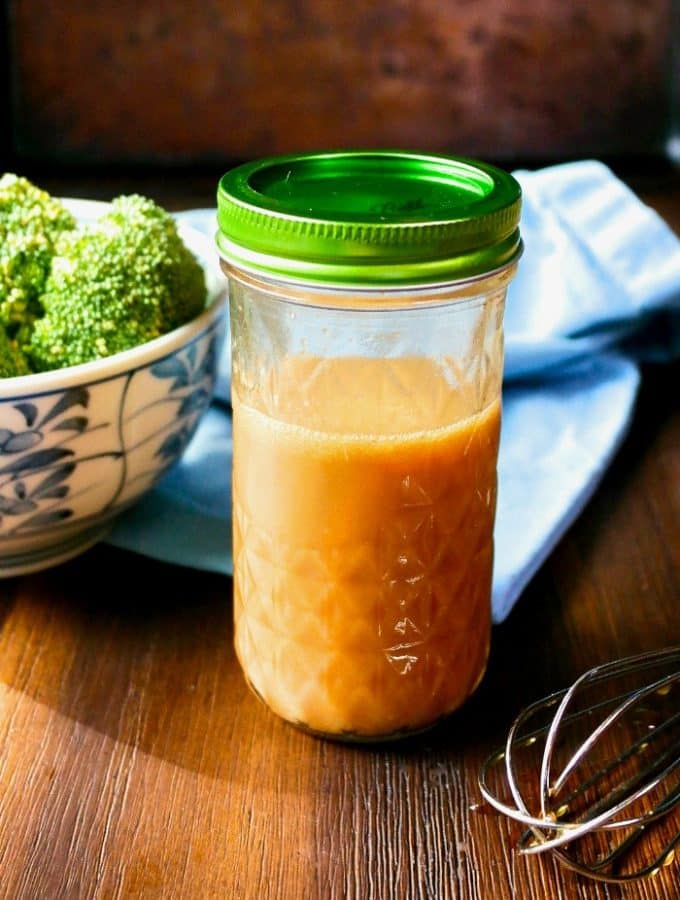 Homemade stir fry sauce in a mason jar with a whisk on the side