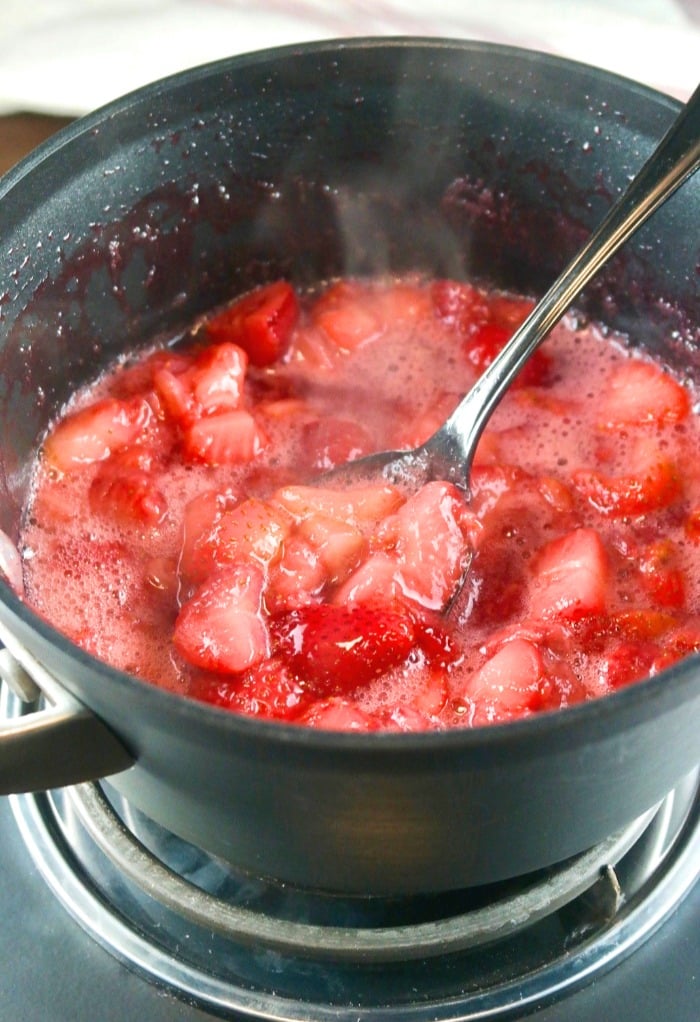 Fresh strawberry puree in a black saucepan cooking