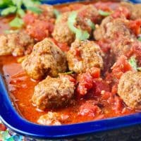 Slow cooked meatballs in a baking dish with a blue rim