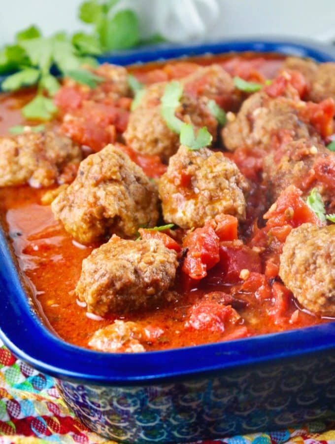 Slow cooked meatballs in a baking dish with a blue rim