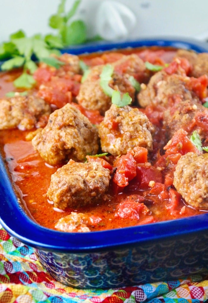 Slow cooked meatballs in a baking dish with a blue rim