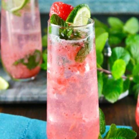 strawberry mojito cocktail in a tall glass with lime and mint