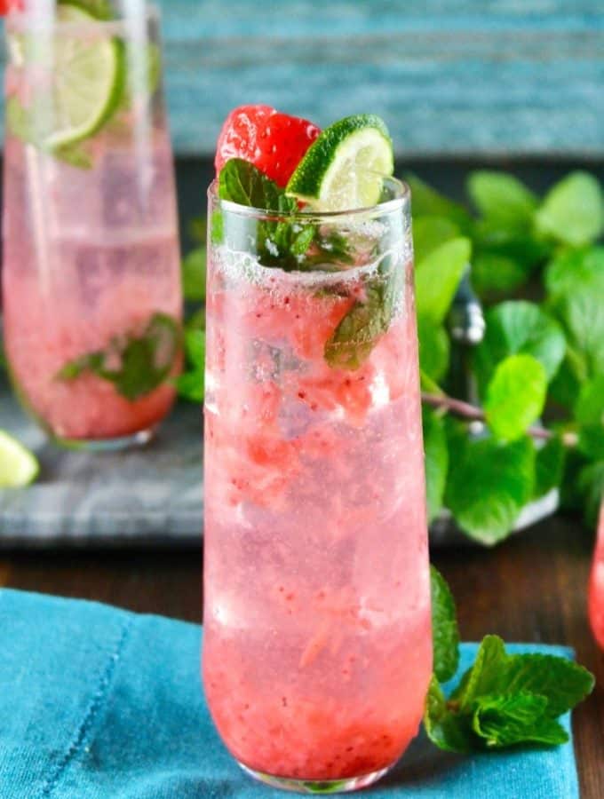 strawberry mojito cocktail in a tall glass with lime and mint