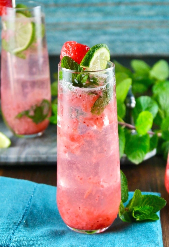 strawberry mojito cocktail in a tall glass with lime and mint