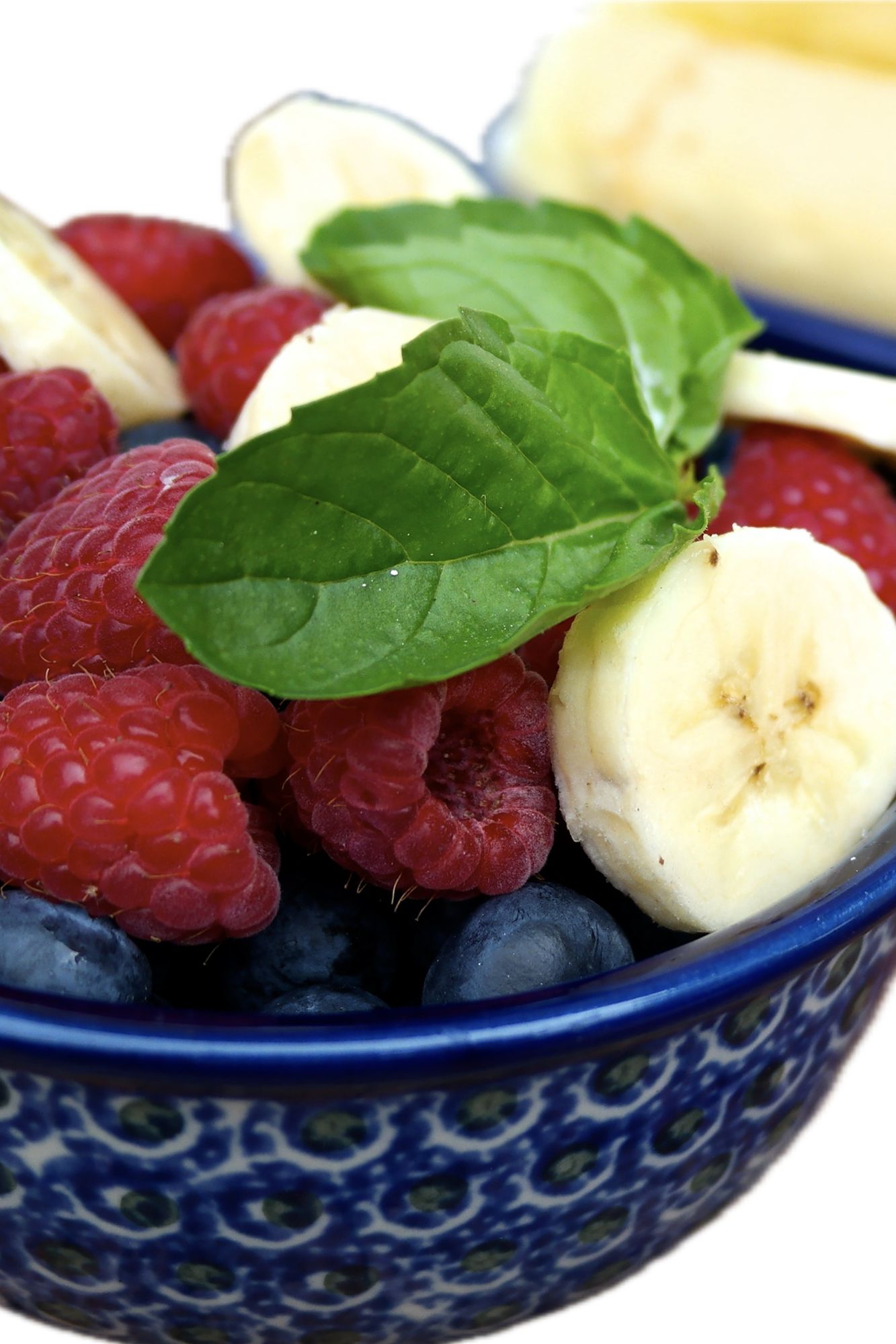 Small blue bowl of fruit to top on cheesecake bites.