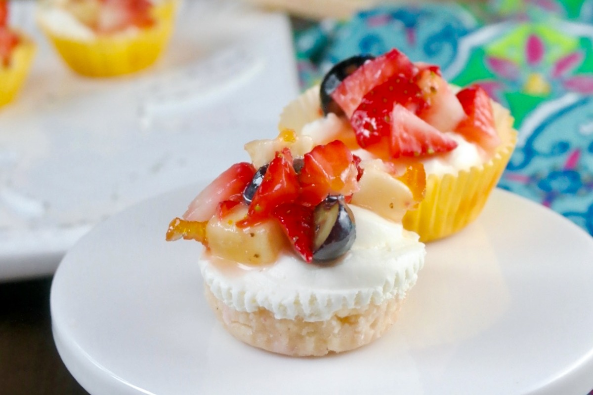 No bake cheesecake bites topped with fruit on a small white serving plate.