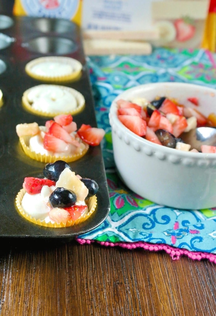 Mini cheesecake recipe in a baking tin topped with fresh fruit