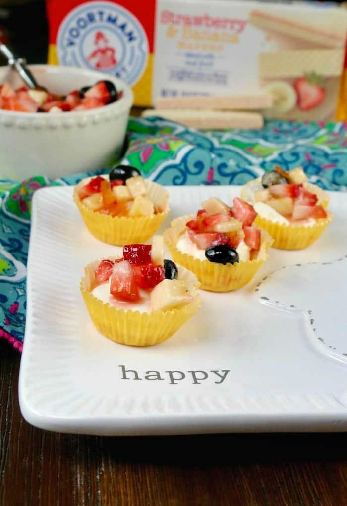 mini cheesecake recipe in yellow cupcake liners on a white plate with the words "happy" written