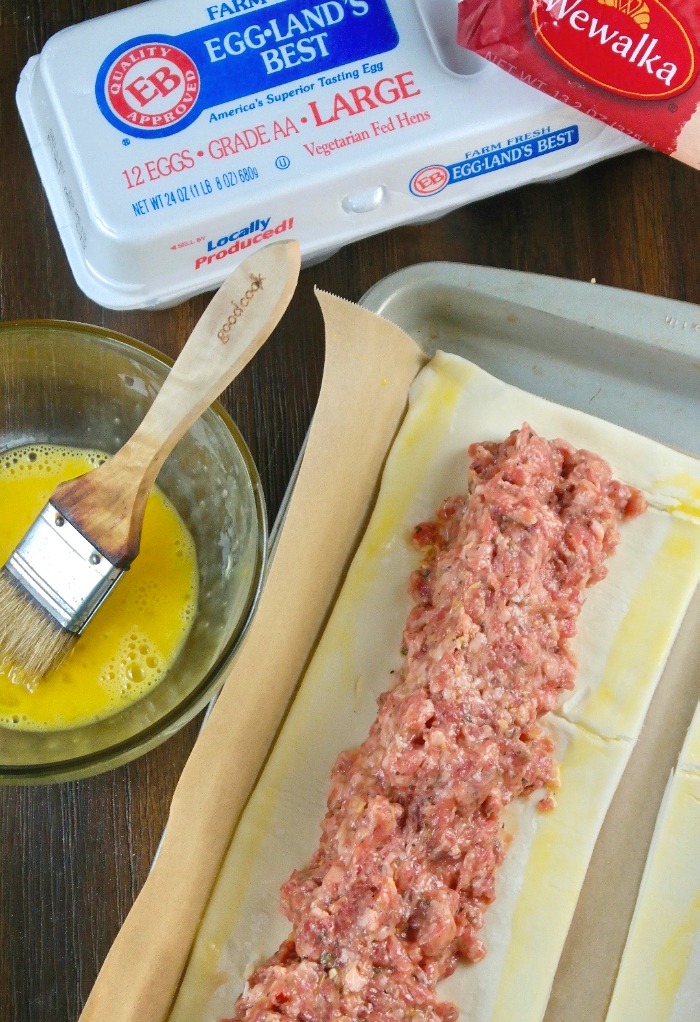 Putting together sausage roll with puff pastry and egg wash