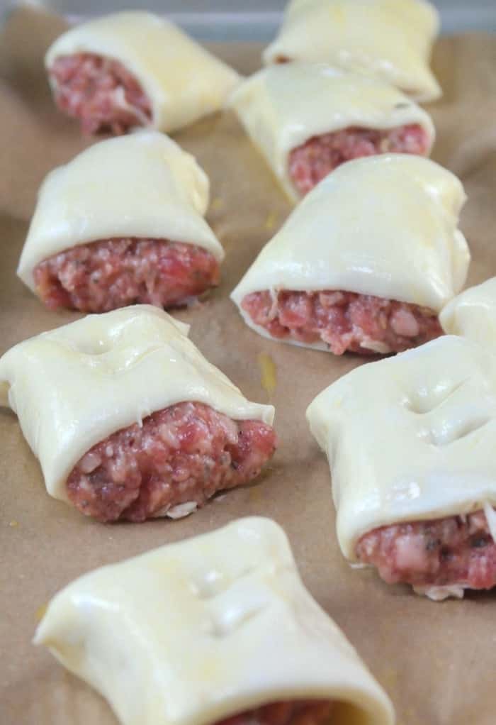 unbaked sausage rolls on parchment paper for baking