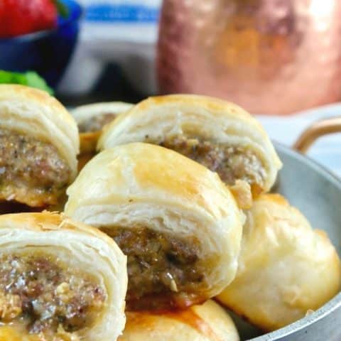 A silver bowl filled with sausage rolls in puff pastry