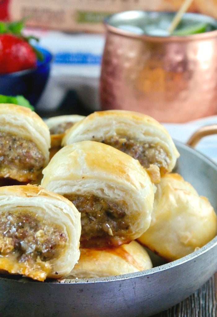 A silver bowl filled with sausage rolls in puff pastry