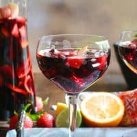 Clear wine glass filled with red Spanish sangria topped with fruit