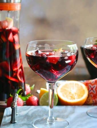 Clear wine glass filled with red Spanish sangria topped with fruit