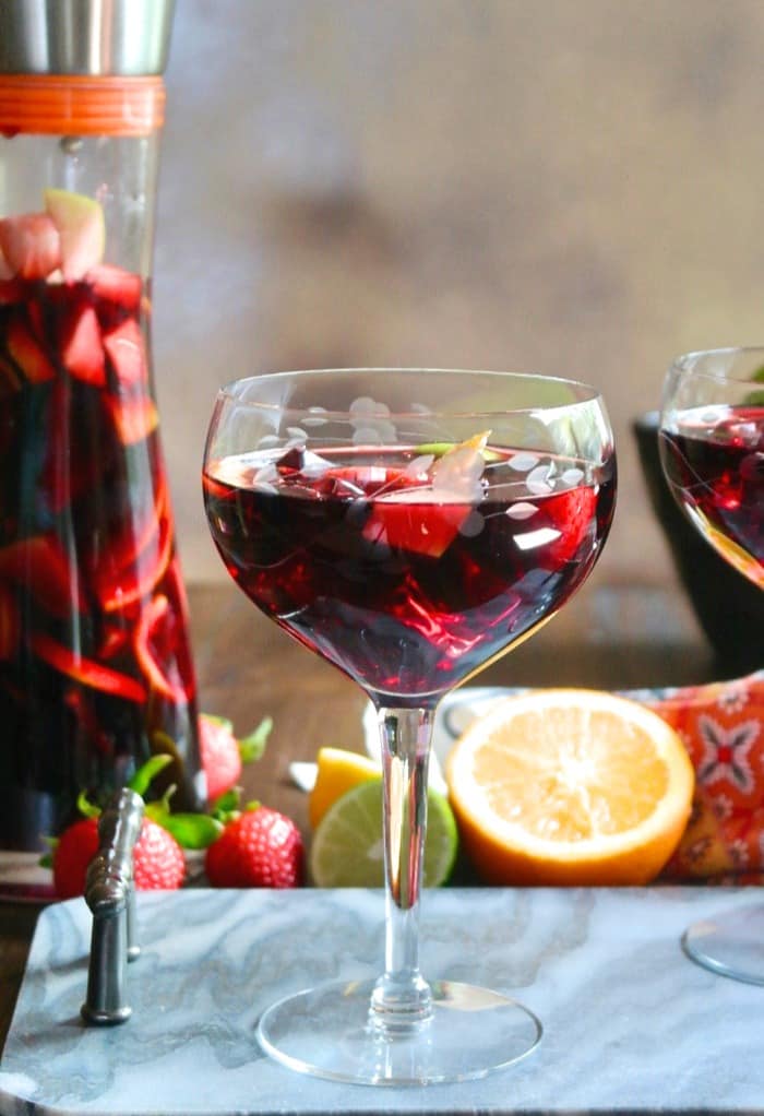 Clear wine glass filled with red Spanish sangria topped with fruit