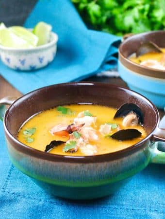 Thai coconut soup with shrimp and muscles in a blue-green soup bowl