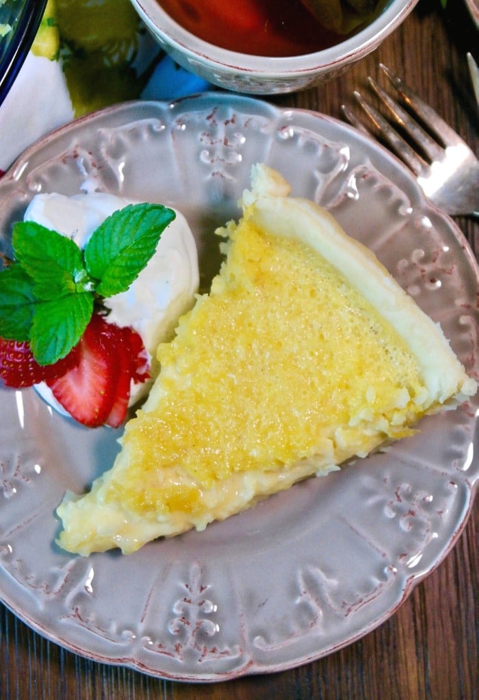 slice of coconut pie on a tan plate with whipped cream on the side