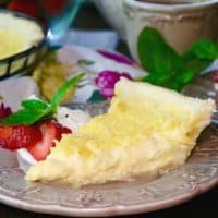 Slice of coconut custard pie on a tan plate with strawberries on the side