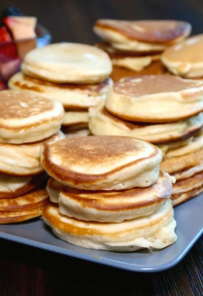 stacks of silver dollar size pancakes on a light blue tray