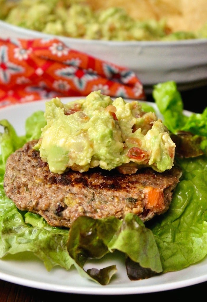 Bunless burger on a lettuce leaf topped with guacamole dip