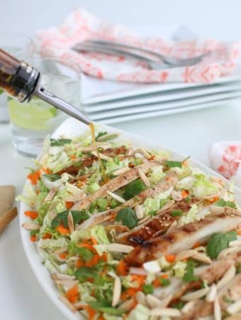 Pouring the salad dressing on our Grilled Ginger Sesame Chicken Salad.
