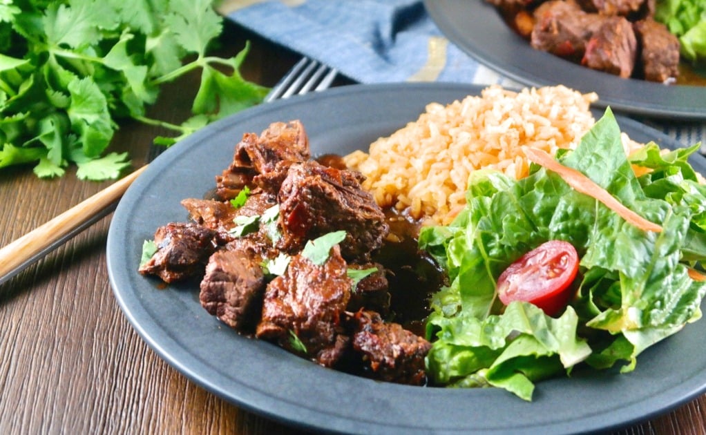 Mexican chili with rice and salad on a black plate. 