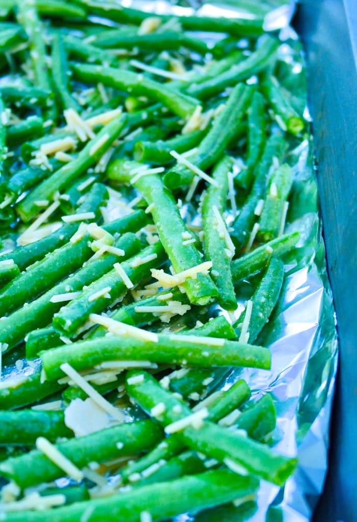 Fresh green beans on a foil lined baking sheet preparing for roasting.