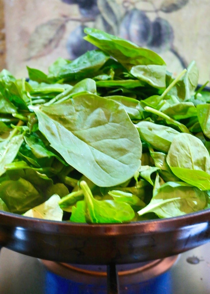 Fresh spinach sautéed in a skillet for spinach casserole.