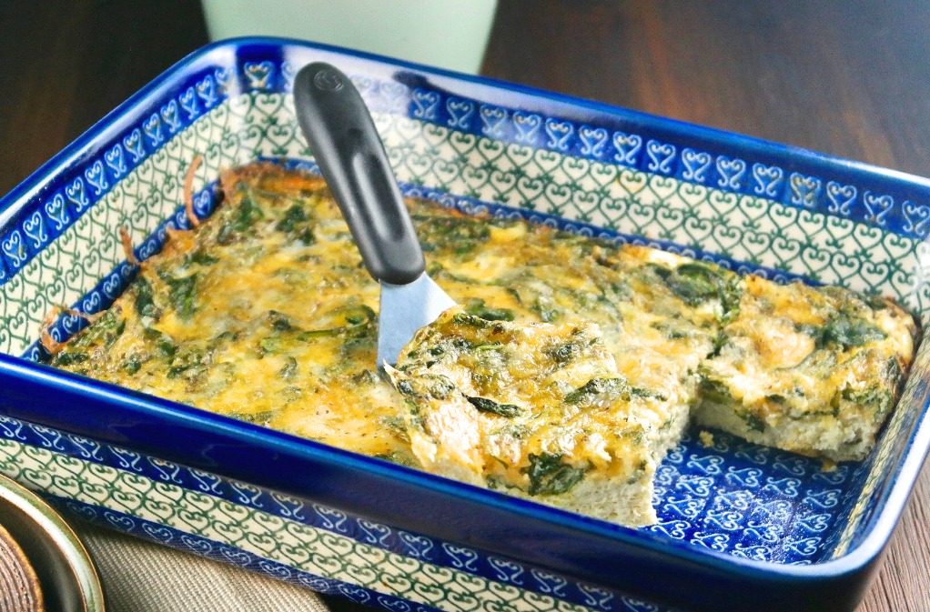 breakfast casserole with spinach in a blue casserole dish