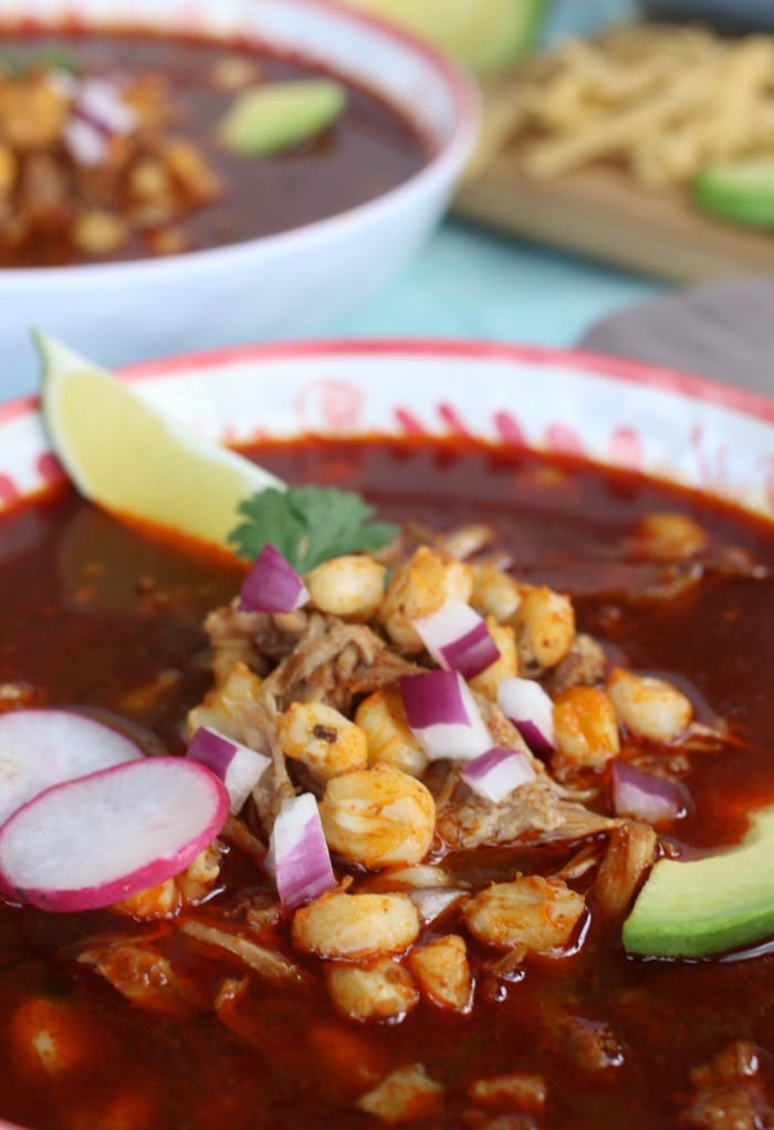 Mexican Soup with hominy garnished with beets, red onion and lime wedges.