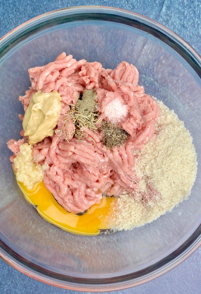 Ingredients for turkey meatballs in a clear mixing bowl.