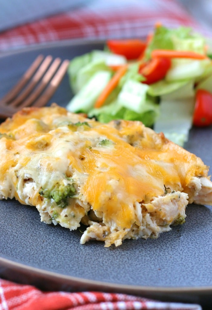 Keto chicken broccoli casserole served up on a plate with a salad ready to be eaten.