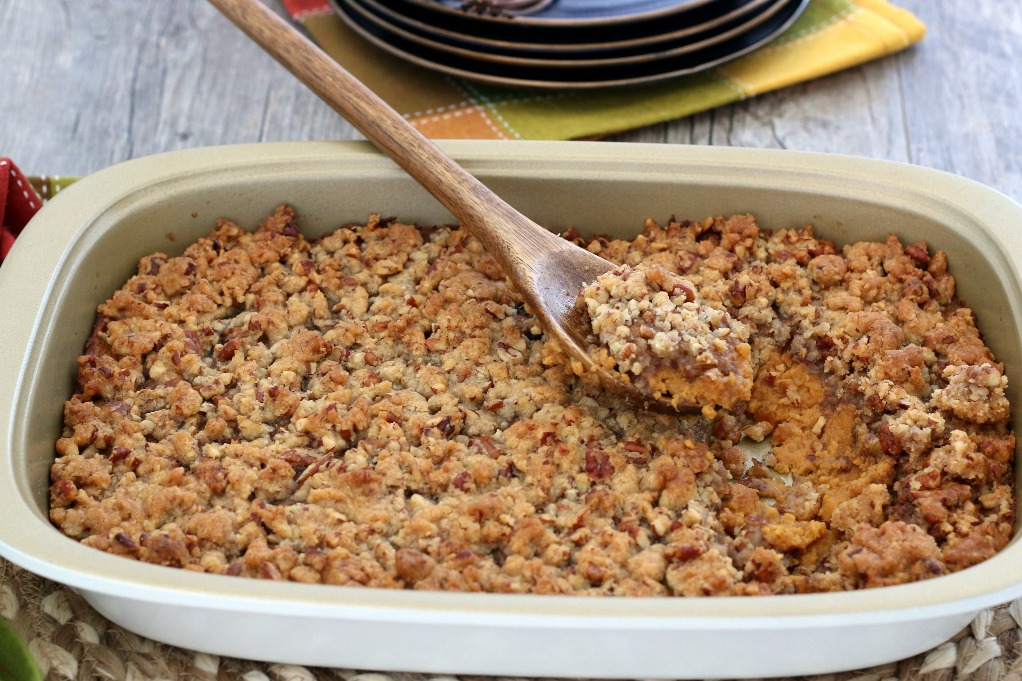 Full view of the finished sweet potato casserole with a scoop taken out of it to be served.