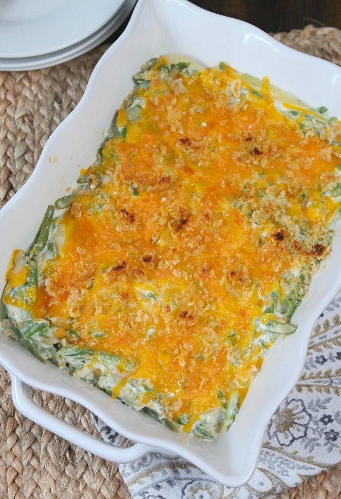 Green bean casserole topped with cheese in a white dish,