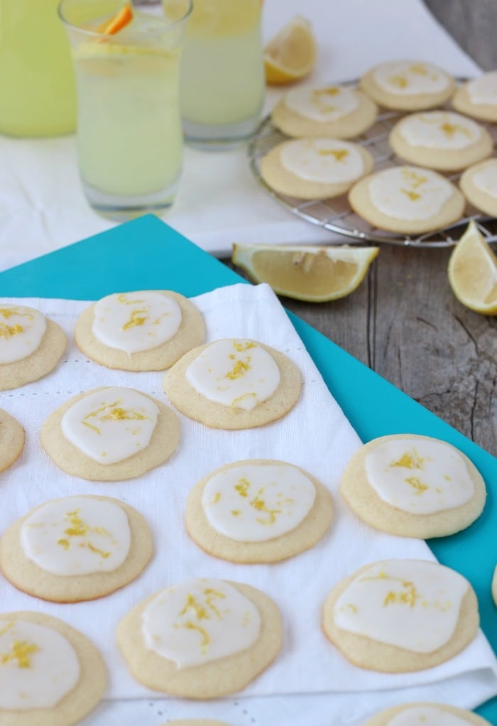 A wider view which shows some of the ricotta cookies finished and on a plate and others on a cooling rack.