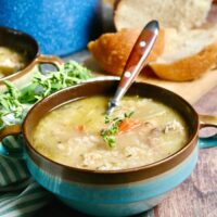 Blue bowl of leftover turkey soup with a brown spoon.