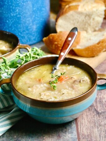 Blue bowl of leftover turkey soup with a brown spoon.