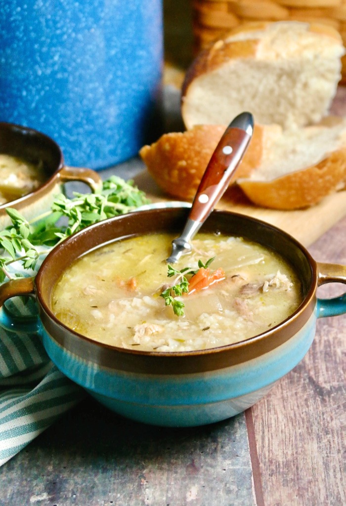 Blue bowl of leftover turkey soup with a brown spoon. 