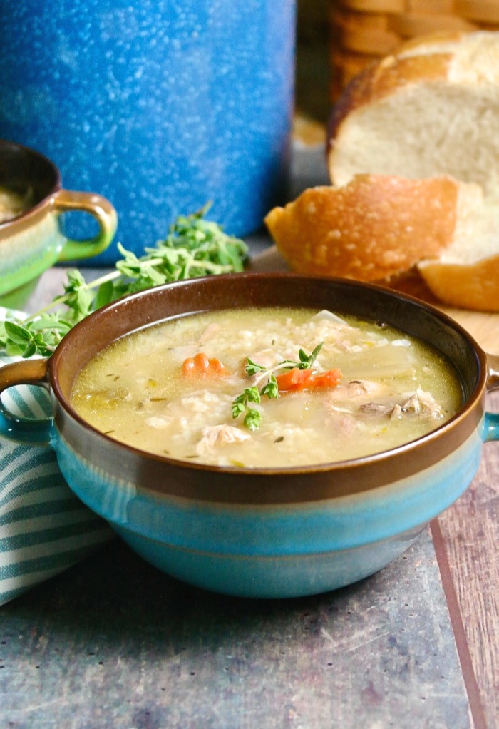 homemade turkey rice soup with a plate of bread in the background