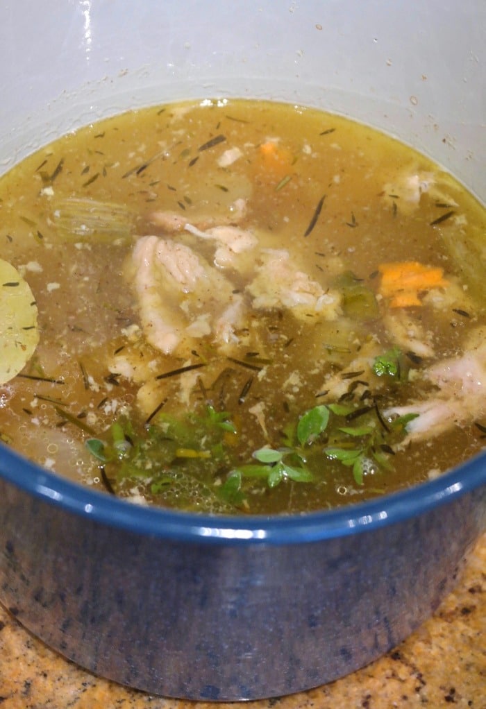 turkey soup simmering in a blue stock pot