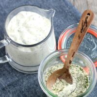 Here we see the glass container of homemade ranch dressing mix next the dry mix