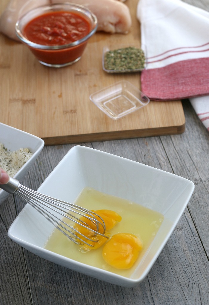 This keto chicken parmesan uses an egg bath to get the parmesan to stick to the chicken.