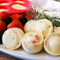 A white plate filled with Instant Pot Egg bites with a red silicone mold in the background.