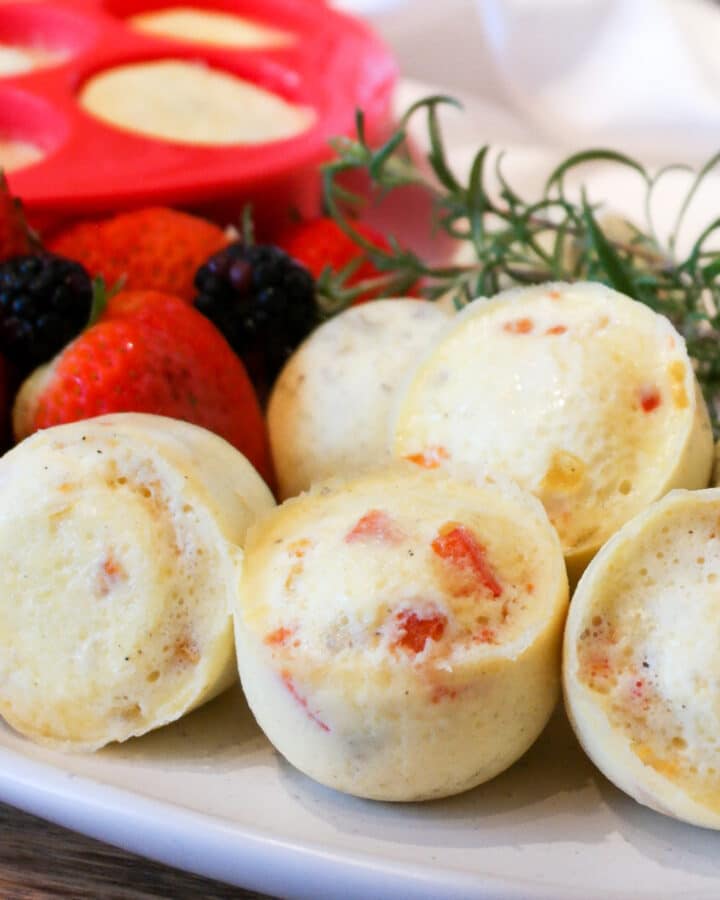 A white plate filled with Instant Pot Egg bites with a red silicone mold in the background.