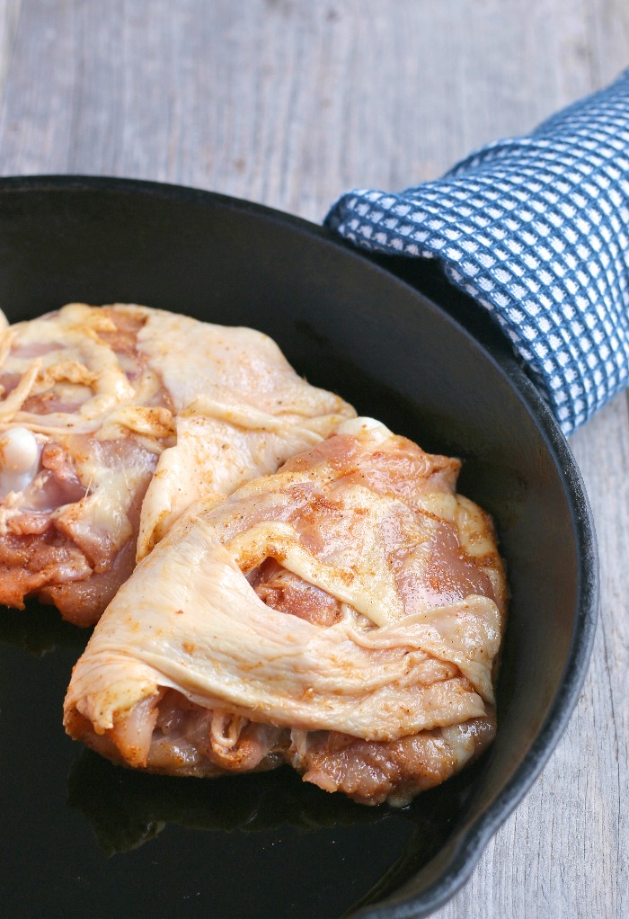 This image shows the chicken thighs in the cast iron skillet ready to be cooked.