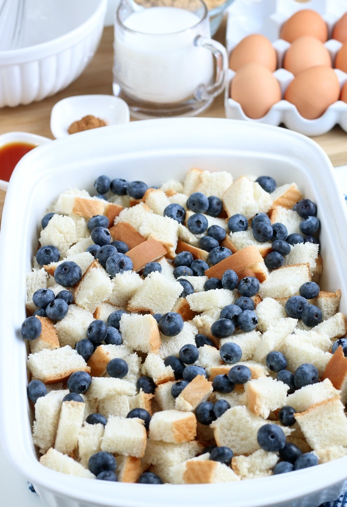 Here we see the start of our french toast casserole, bread and berries being added to the casserole dish.